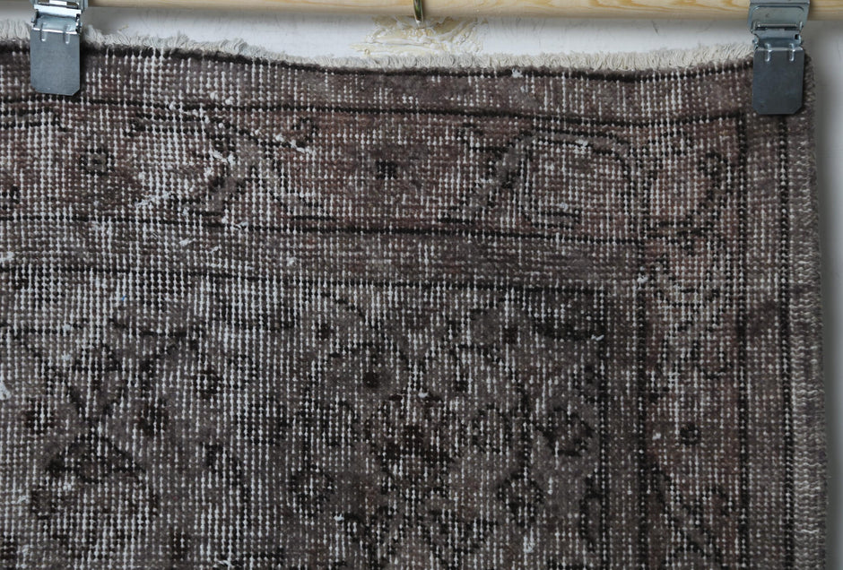 Close-up of handmade wool cotton rug showing distressed dark floral weave texture