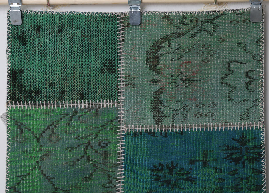 Full vintage patchwork runner rug hanging showing emerald green panels with overdyed floral print