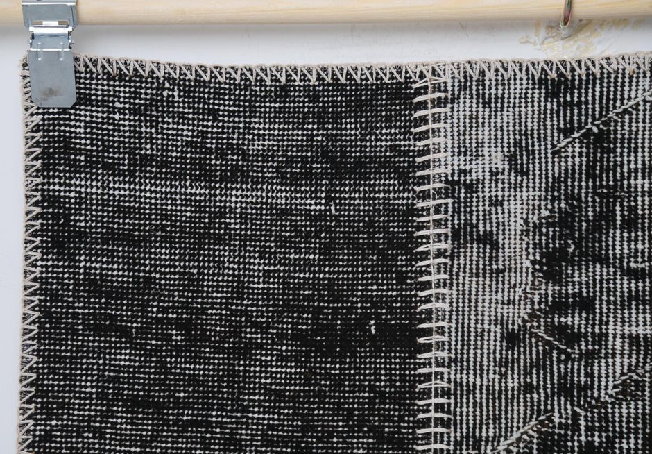 Close-up of handmade wool cotton rug showing black distressed weave with white stitched border