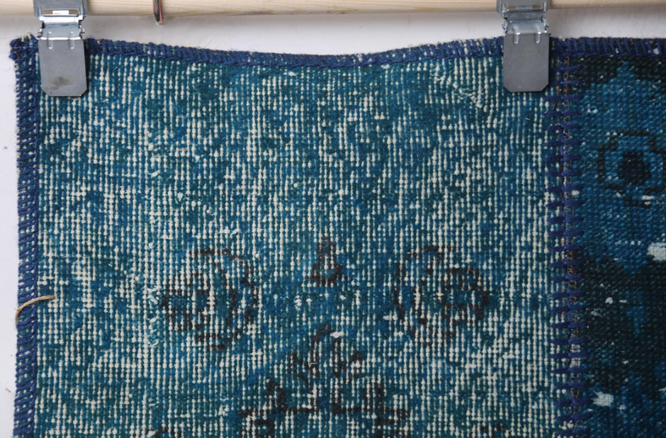 Close-up of vintage Turkish runner rug texture showing floral medallion motif in deep blue