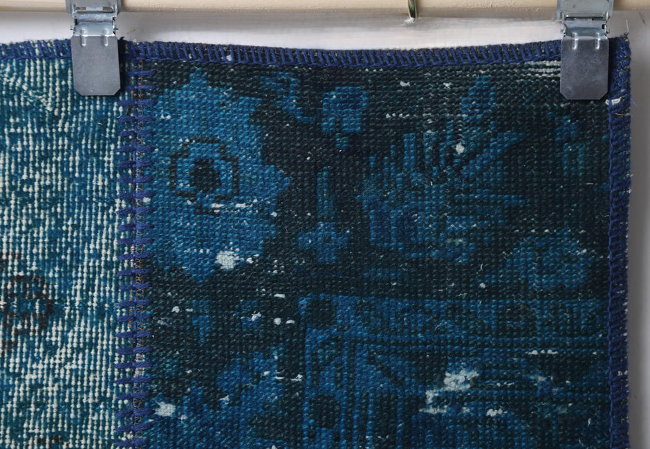 Full vintage patchwork runner rug hanging showing teal blue panels with faded floral print