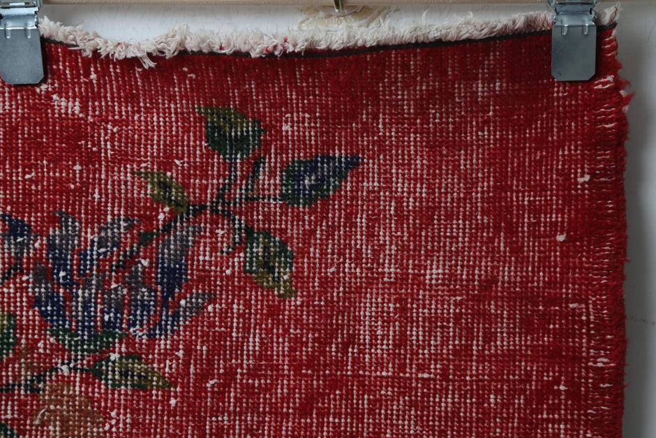 Full vintage Turkish runner rug hanging showing worn red floral pattern hallway rug