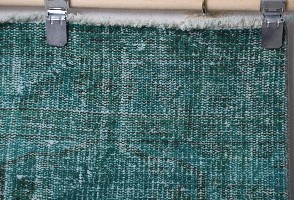 Close-up of handmade wool cotton runner rug showing worn teal green weave texture