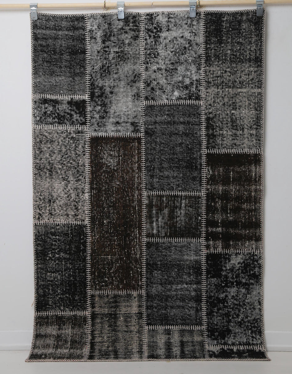Close-up of vintage Turkish rug corner showing dark brown and black distressed panel texture
