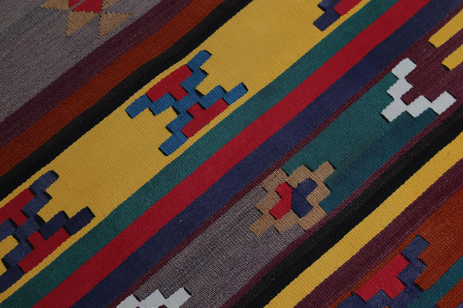 Detail shot of vintage Turkish runner rug texture showing colorful tribal diamond and zigzag motifs