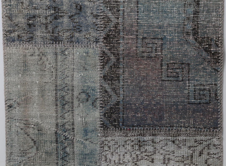 Close-up of handmade wool cotton runner rug showing faded gray blue vintage pattern texture