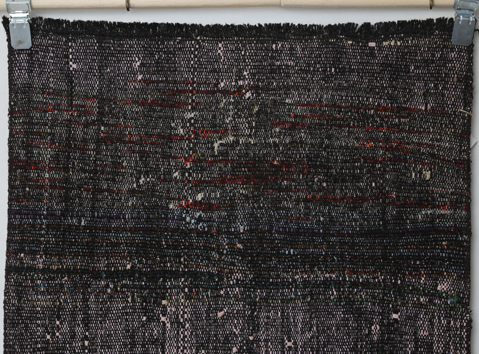 Detail shot of vintage Turkish runner rug texture showing dark distressed striped weave