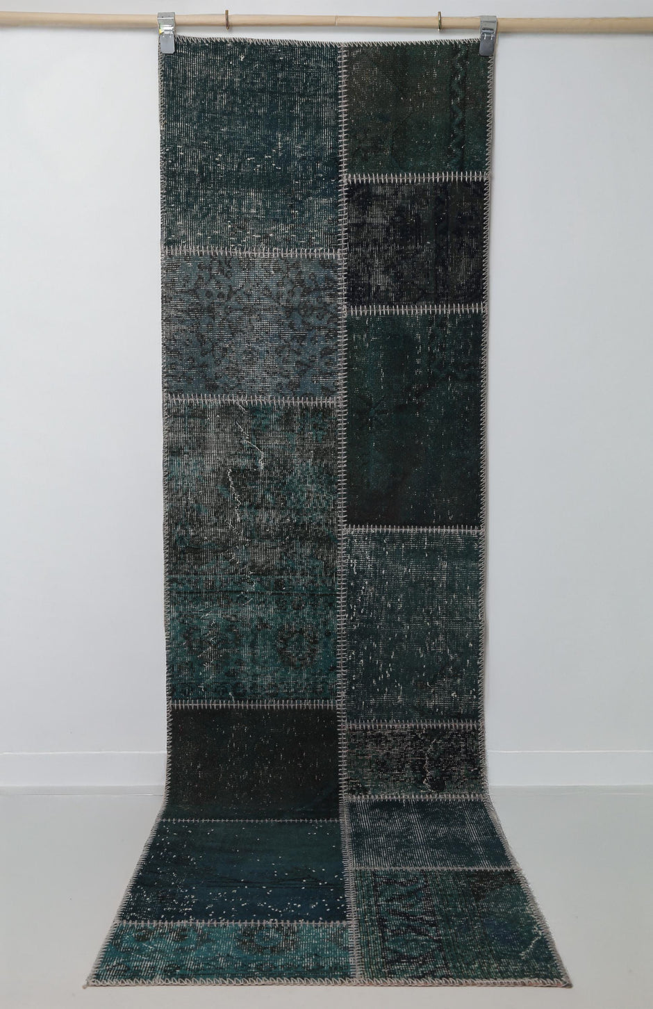 Close-up of vintage Turkish runner rug texture showing dark green distressed woven panel