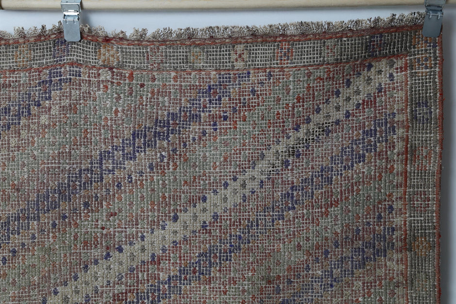 Close-up of handmade wool kilim rug showing faded diagonal pattern in earthy tones