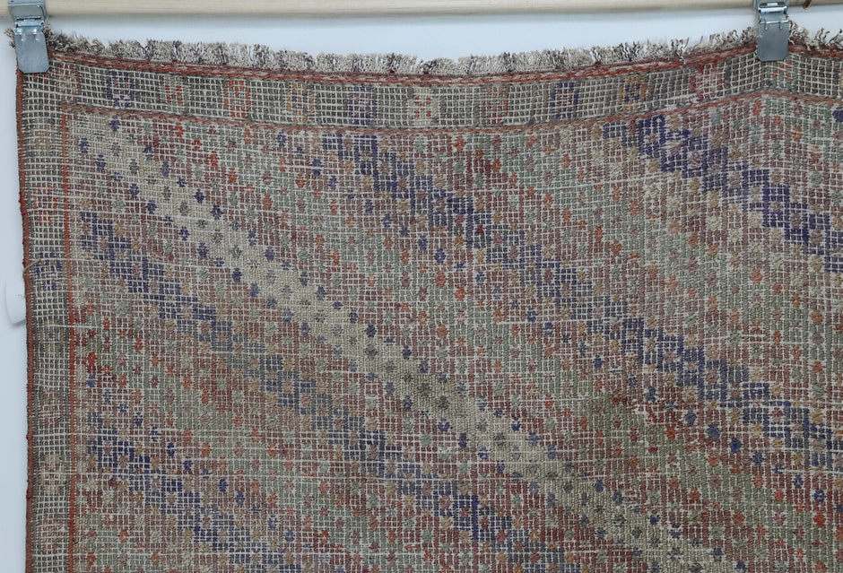 Close-up of vintage Turkish kilim rug showing muted brown, blue and rust diagonal stripes