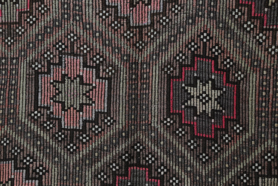 Detail shot of vintage Turkish kilim rug weave showing tribal star pattern in brown, pink and green