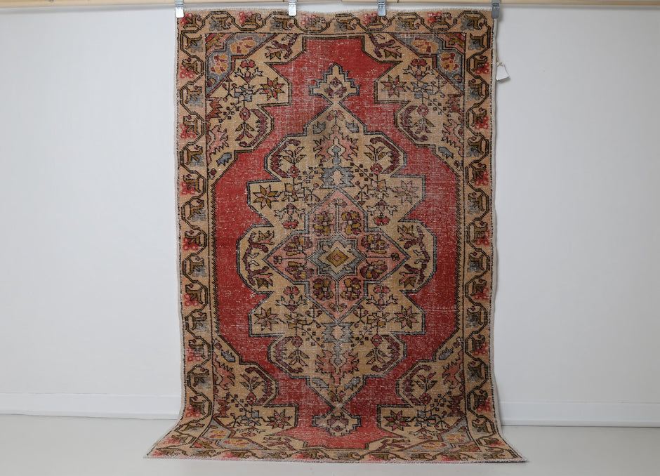 Close-up of geometric medallion detail on red beige oriental rug