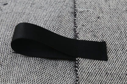 A black fabric loop or strap laid on a textured gray woven surface.