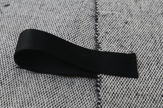 A black fabric loop or strap laid on a textured gray woven surface.
