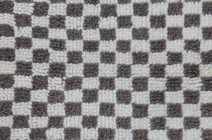 A close-up of a black and white checkerboard patterned plush rug or carpet texture.