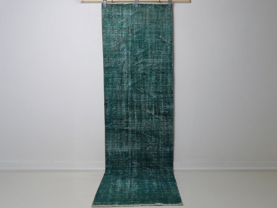 2'4 x 8'7 vintage Turkish runner rug hanging showing solid teal green distressed weave