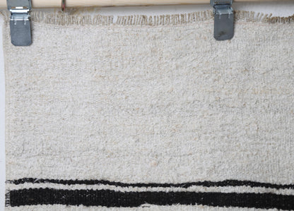 Close-up of handmade natural fiber runner rug showing thick white weave with black stripe accents