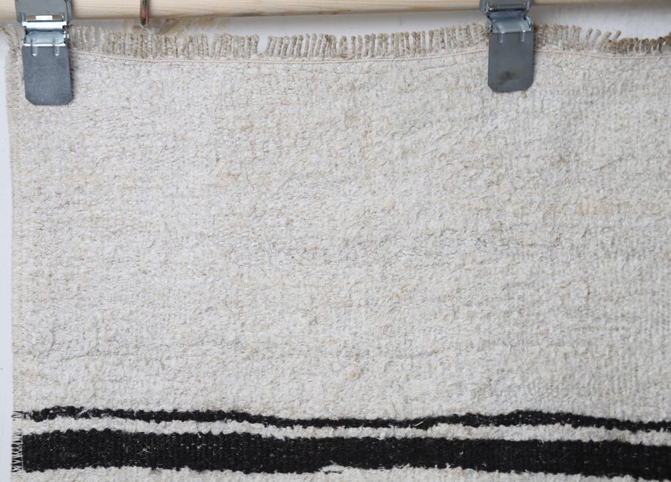 Close-up of handmade natural fiber runner rug showing thick white weave with black stripe accents