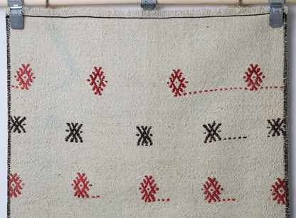 Detail shot of vintage Turkish runner rug texture showing scattered tribal diamond pattern on beige