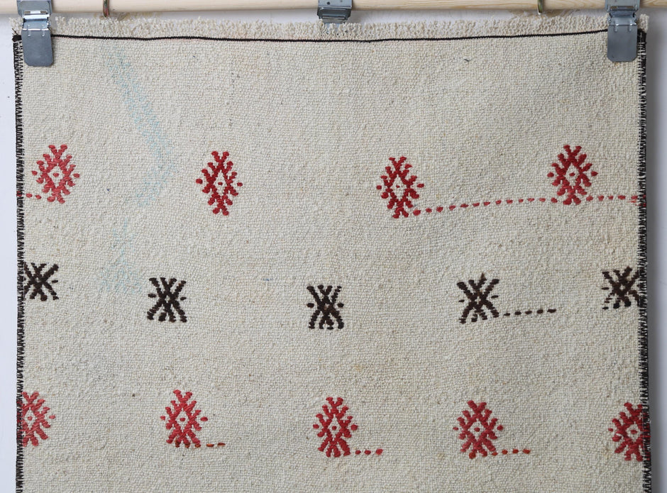 Detail shot of vintage Turkish runner rug texture showing scattered tribal diamond pattern on beige