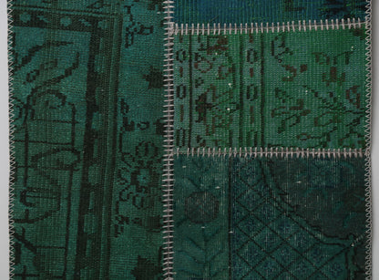 Detail shot of vintage Turkish patchwork rug panel showing deep green overdyed floral pattern