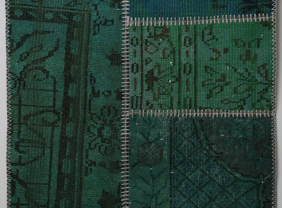 Detail shot of vintage Turkish patchwork rug panel showing deep green overdyed floral pattern