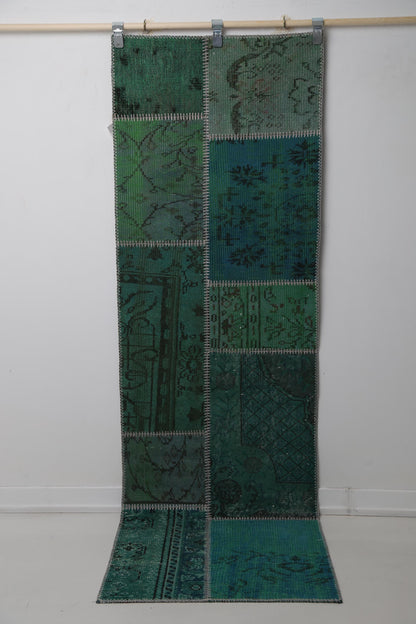 Close-up of vintage Turkish runner rug panel showing faded floral motif on deep green field