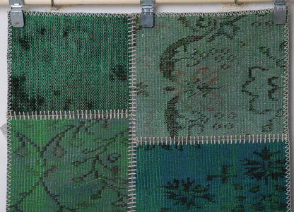 Full vintage patchwork runner rug hanging showing emerald green panels with overdyed floral print