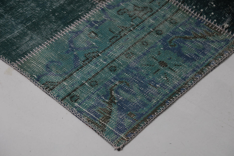 Full vintage patchwork runner rug hanging showing rich teal green panels with black accent panel