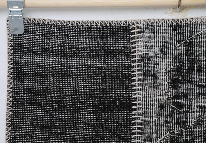 Close-up of handmade wool cotton rug showing black distressed weave with white stitched border