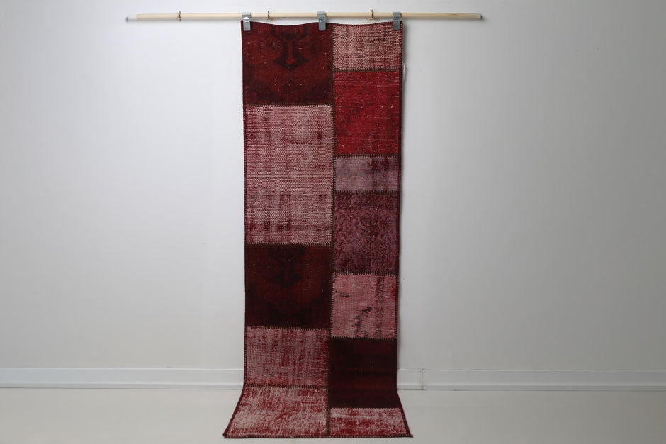 2'5 x 7'6 vintage Turkish patchwork runner rug hanging showing rich red overdyed panel design