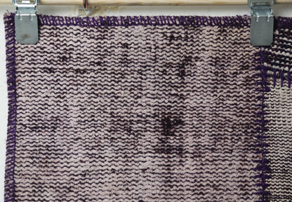 Close-up of vintage Turkish runner rug texture showing deep purple distressed woven panel