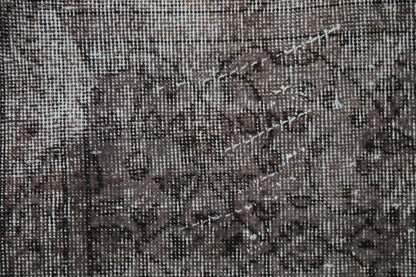 Detail shot of vintage Turkish rug texture showing faint floral pattern on charcoal brown field