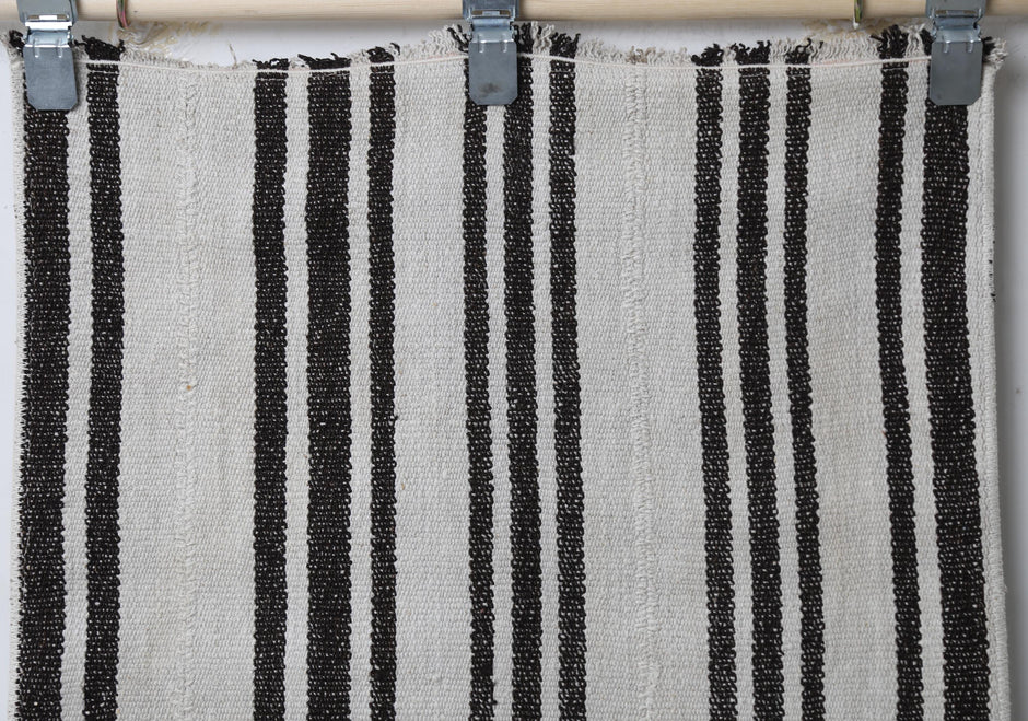 Full vintage hemp runner rug hanging showing long white and black vertically striped hallway rug