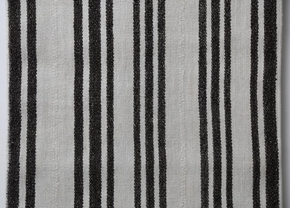 Detail shot of vintage Turkish runner rug texture showing black vertical stripe pattern on white fabric