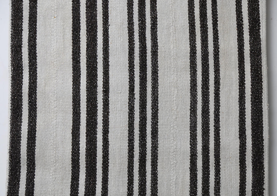 Close-up of handmade natural fiber runner rug showing pinstripe black lines on cream weave