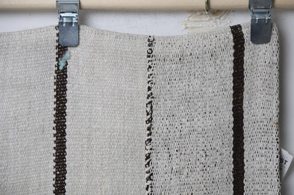 Close-up of handmade natural fiber runner rug showing thin black stripe line on cream fabric