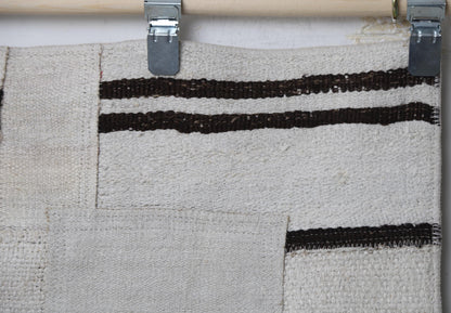 Close-up of handmade natural fiber runner rug showing scattered black dash patchwork marks on cream
