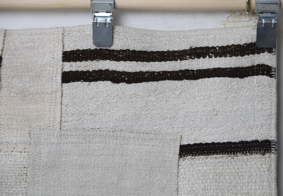 Close-up of handmade natural fiber runner rug showing scattered black dash patchwork marks on cream