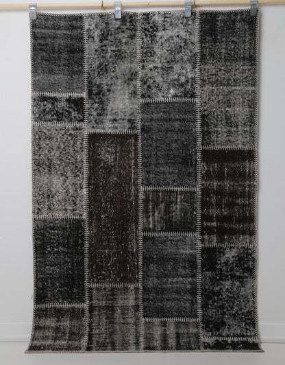 Close-up of vintage Turkish rug corner showing dark brown and black distressed panel texture