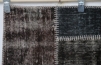  Full vintage patchwork rug hanging showing black brown speckled panels with stitched seams