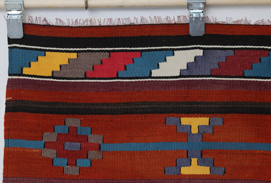 Vintage tribal kilim runner detail showing geometric hourglass motifs in blue and rust
