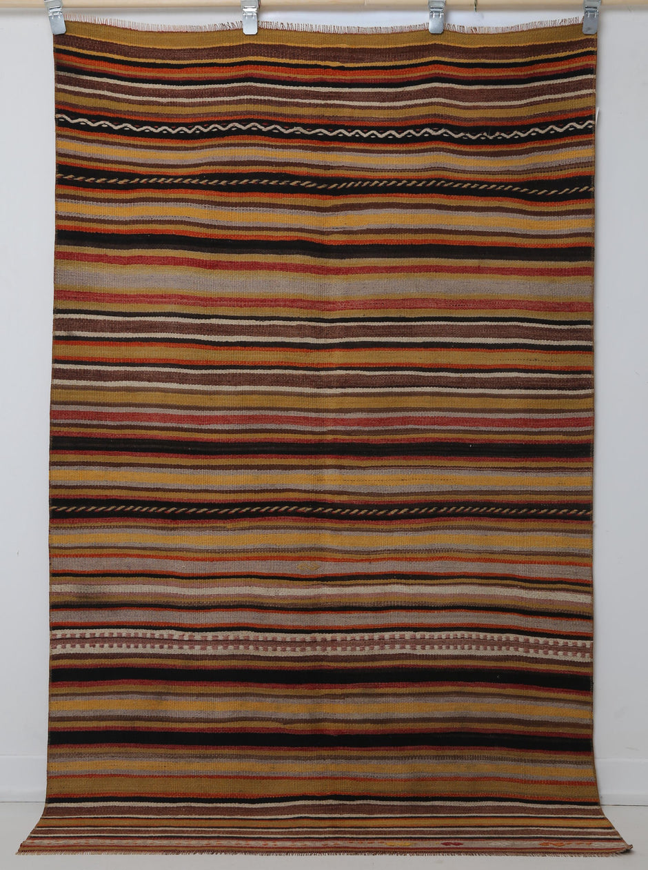 Close-up of vintage Turkish flatweave rug corner showing red, orange and brown striped weave