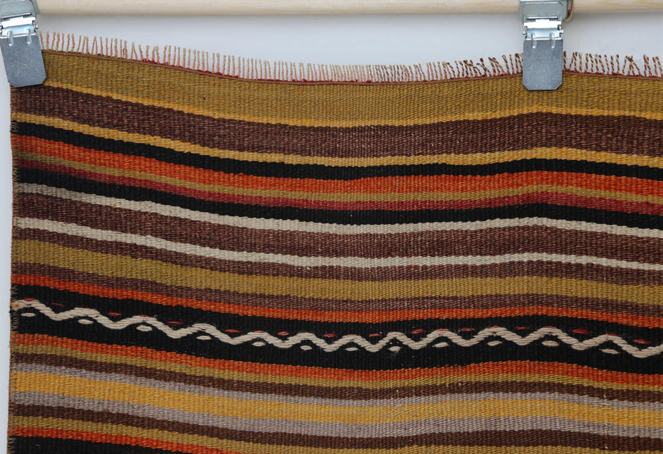 Close-up of handmade wool flatweave rug showing zigzag black stripe accent on striped field