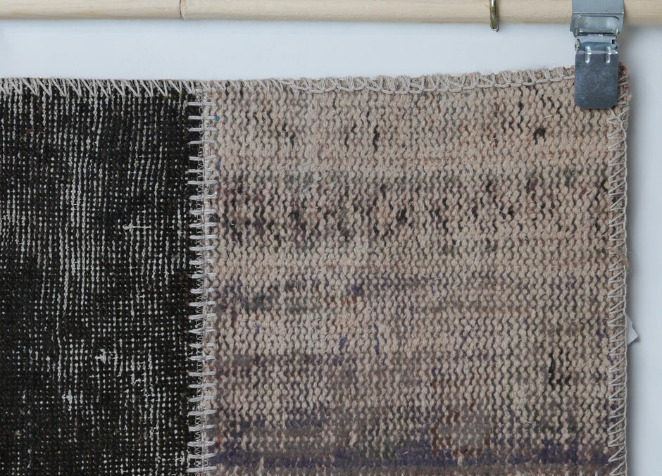 Close-up of handmade wool cotton runner rug showing faded tan and black distressed panel texture