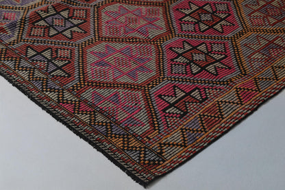 Close-up of vintage Turkish kilim rug showing red, orange and pink hexagon medallion design
