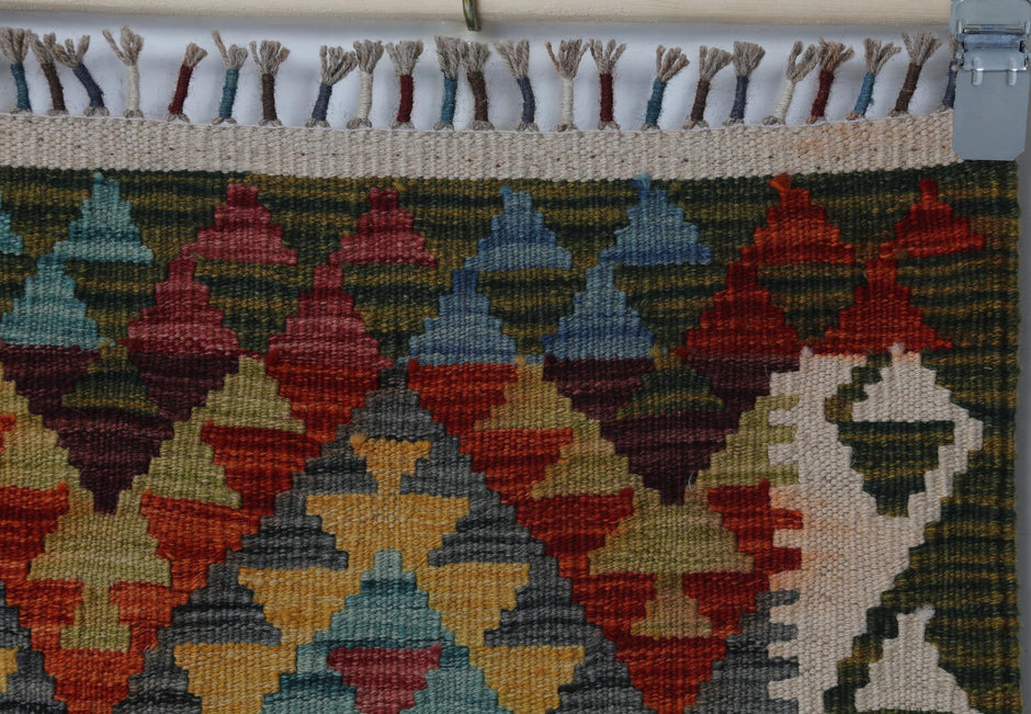 Detail shot of vintage Turkish rug weave showing tribal triangle motifs with fringe edge