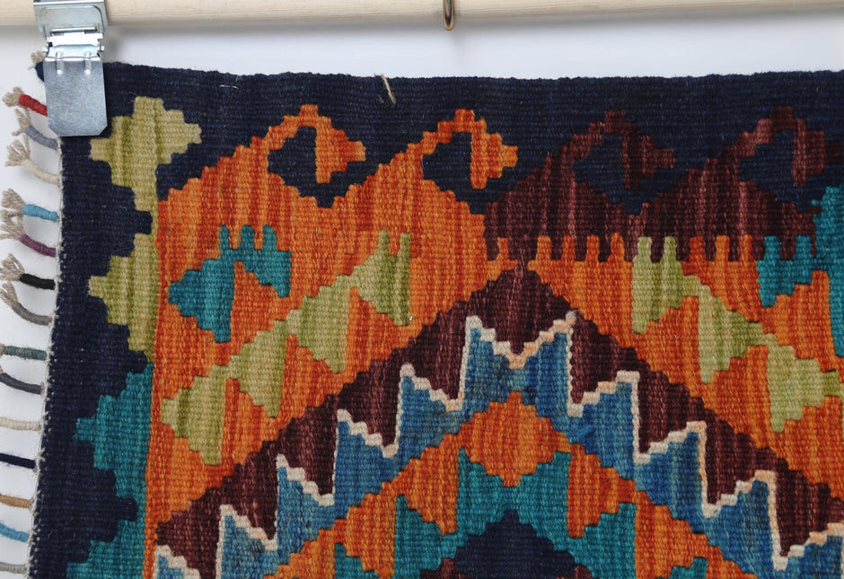 Close-up of vintage Turkish small rug showing orange, green and blue zigzag pattern