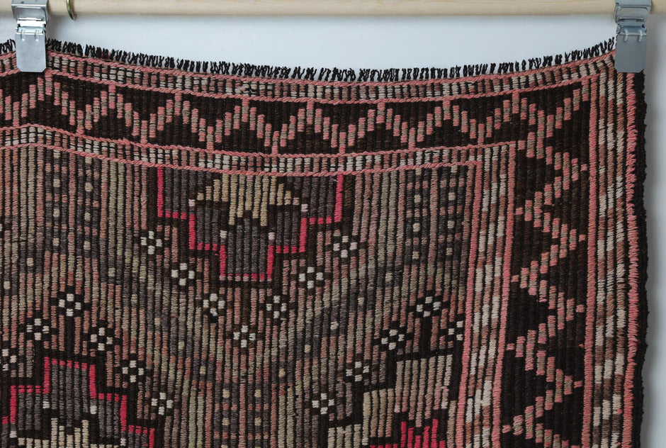 Close-up of handmade wool kilim rug showing star medallion motifs in pink and brown