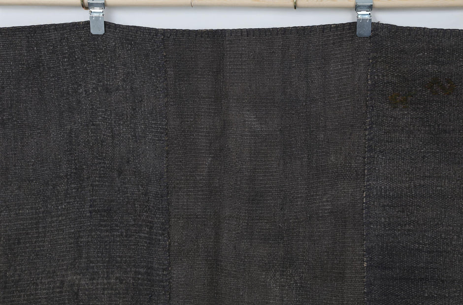 Full vintage hemp patchwork rug hanging showing dark brown panel seams and texture